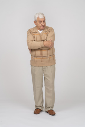 Front view of an old man in casual clothes standing with crossed arms