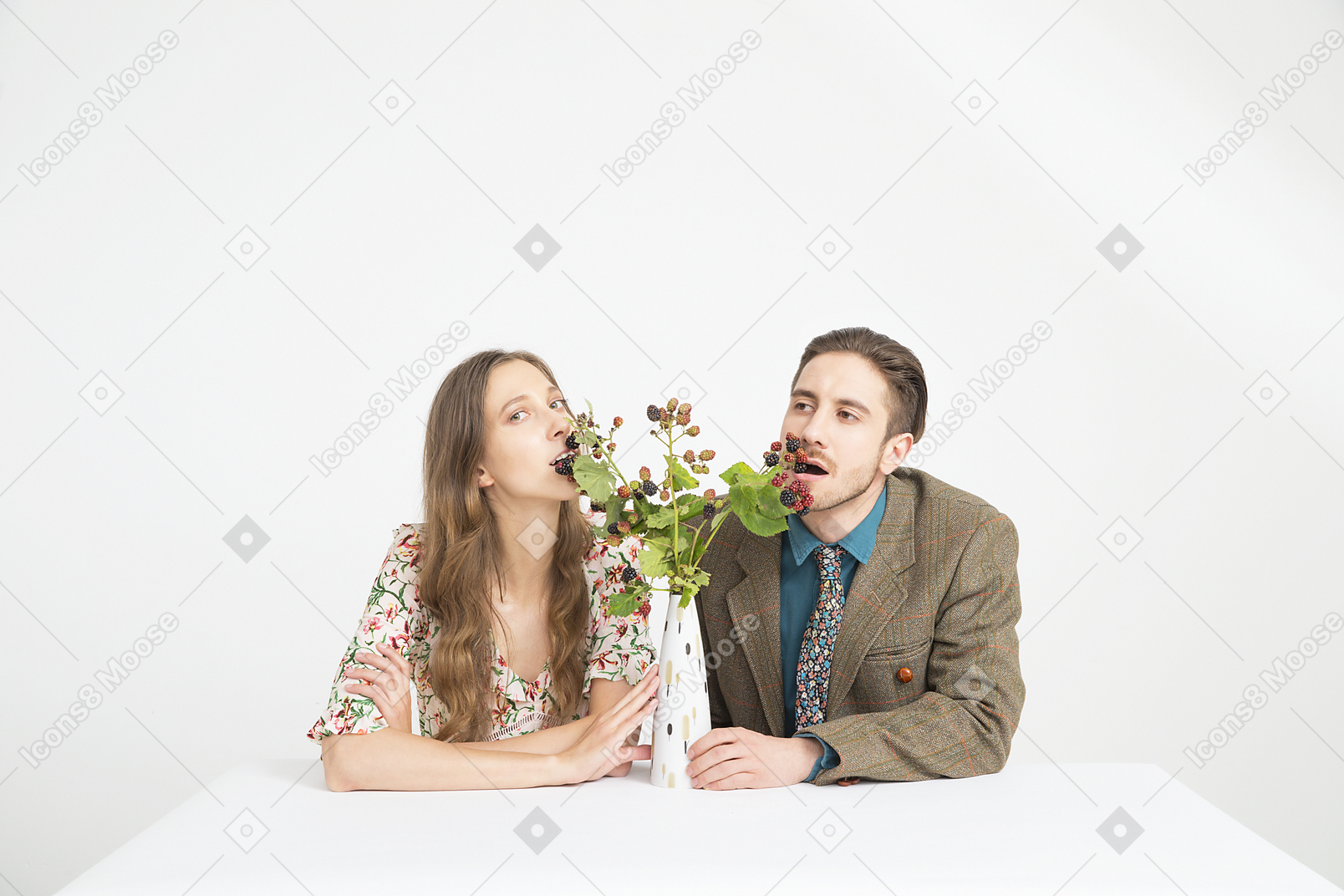 Couple sitting at the table and eating blackberries from the branches in vase