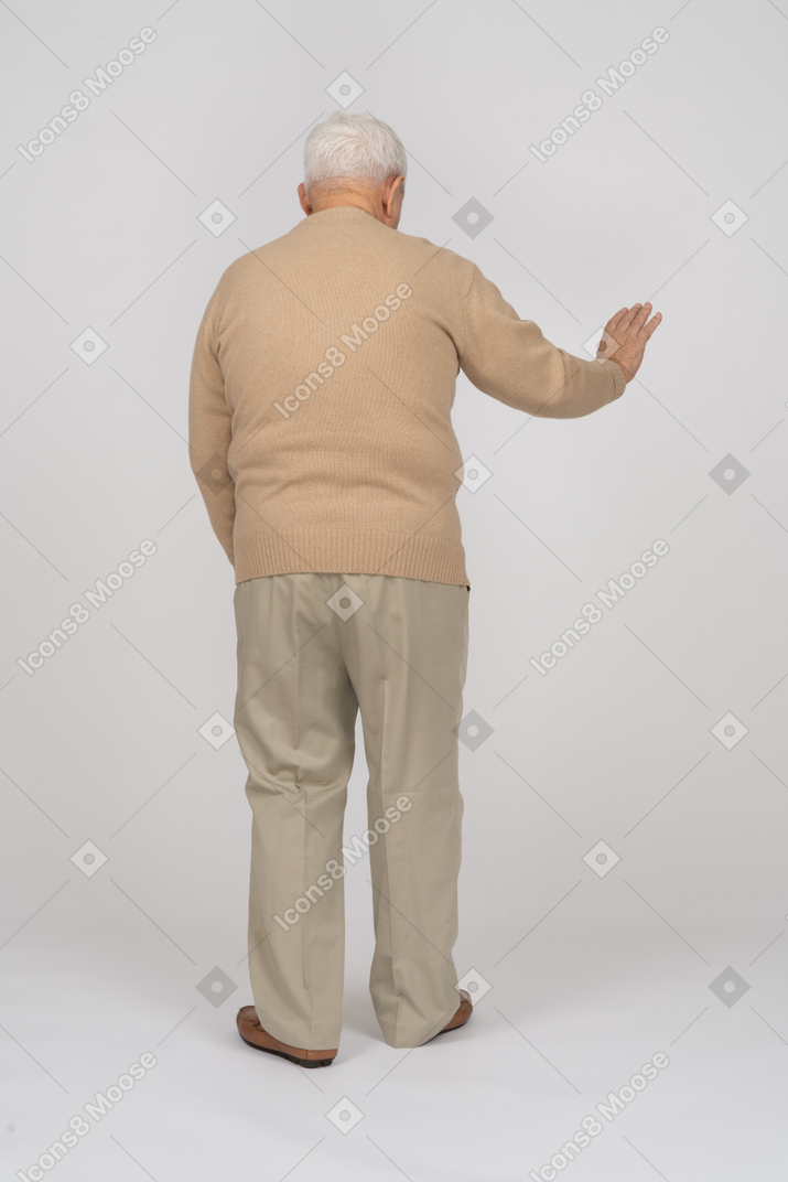 一位穿着休闲服的老人伸出手臂站立的后视图