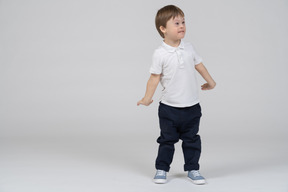 Confused little boy standing with arms at sides