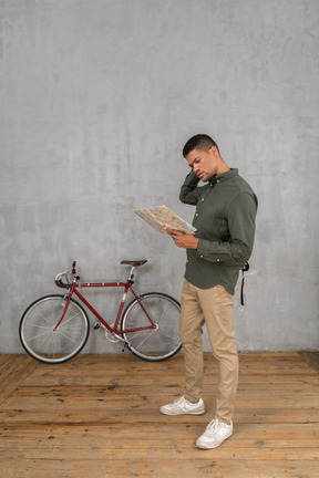 Three-quarter view of a man examining a map looking troubled