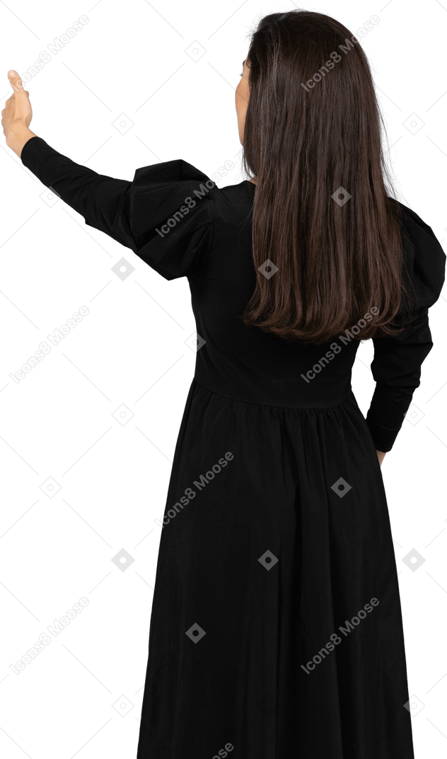 Vista traseira de uma jovem em um vestido preto com o polegar para cima