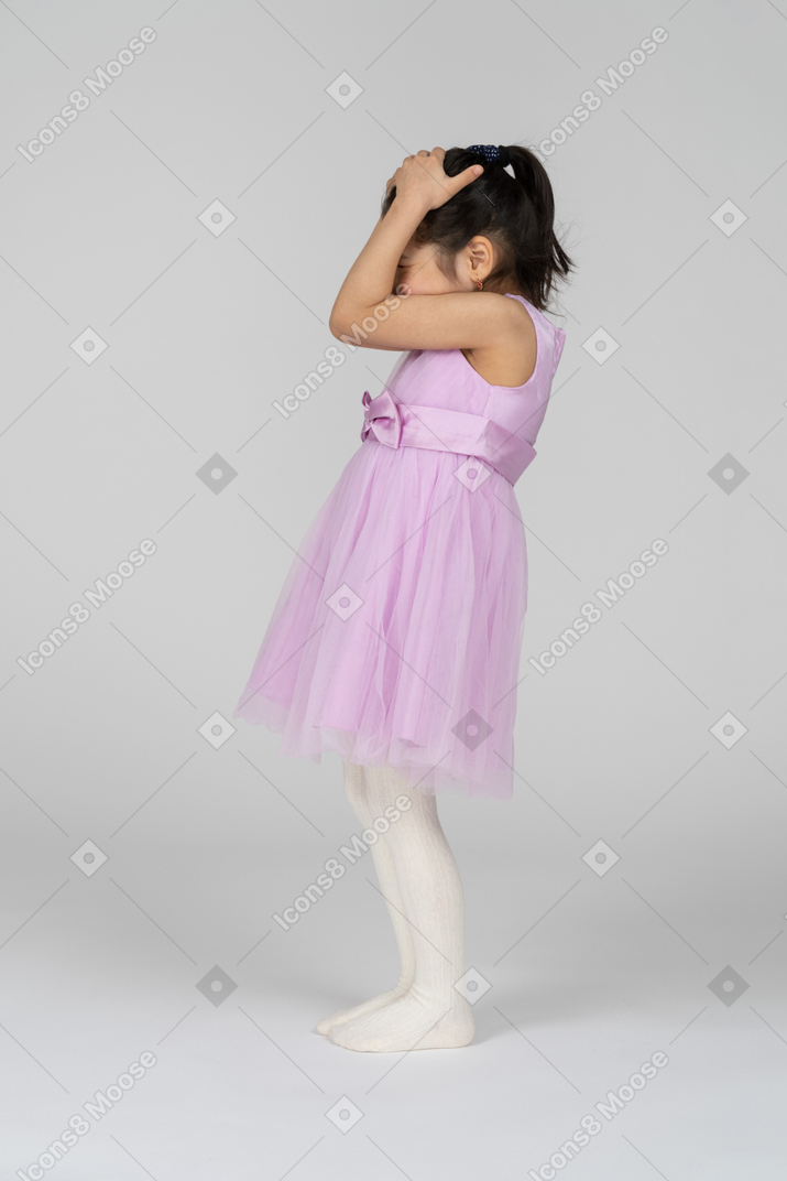 Side view of a little girl in a pretty dress covering her head