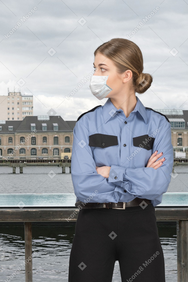 A woman wearing a face mask standing in front of a body of water