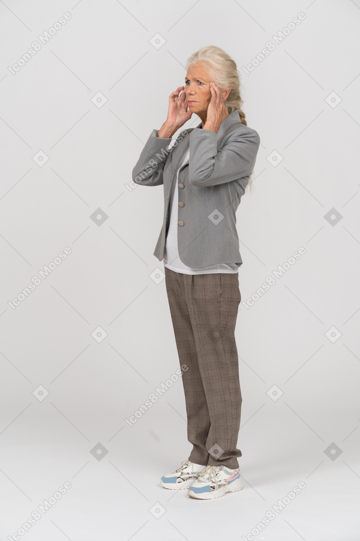 Side view of an old lady in suit touching her face