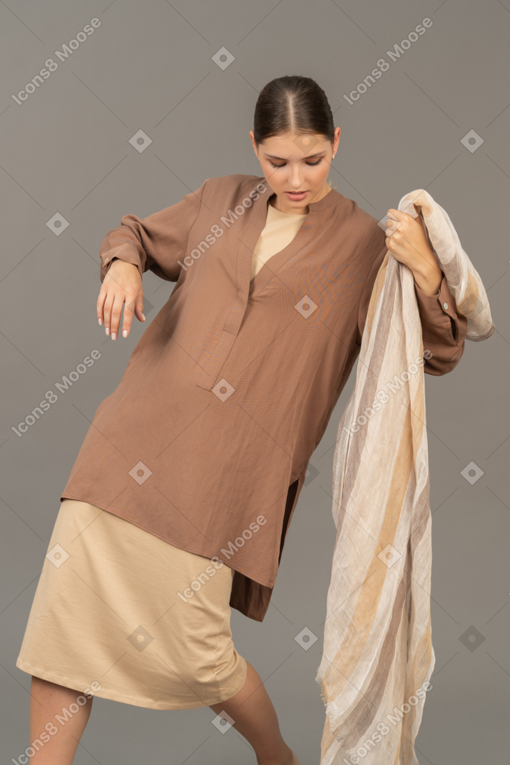 스카프로 포즈를 취하는 베이지색 옷을 입은 젊은 여성