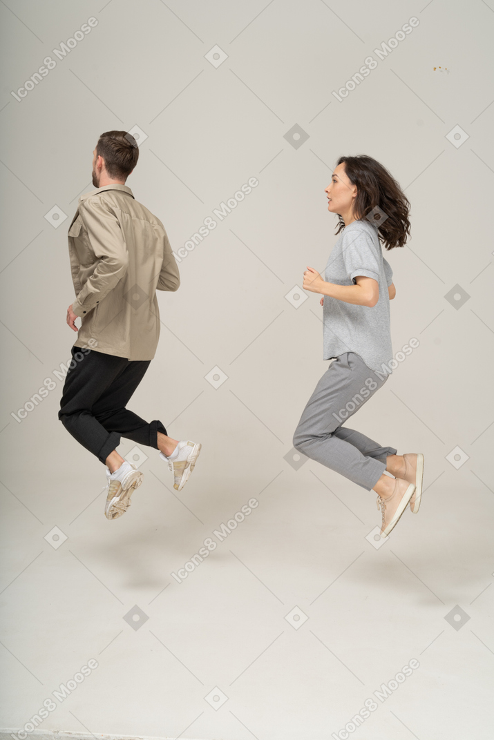 Side view of young woman and man in the air  with bent legs
