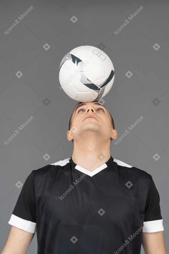Front view of a male football player holding a ball on his head