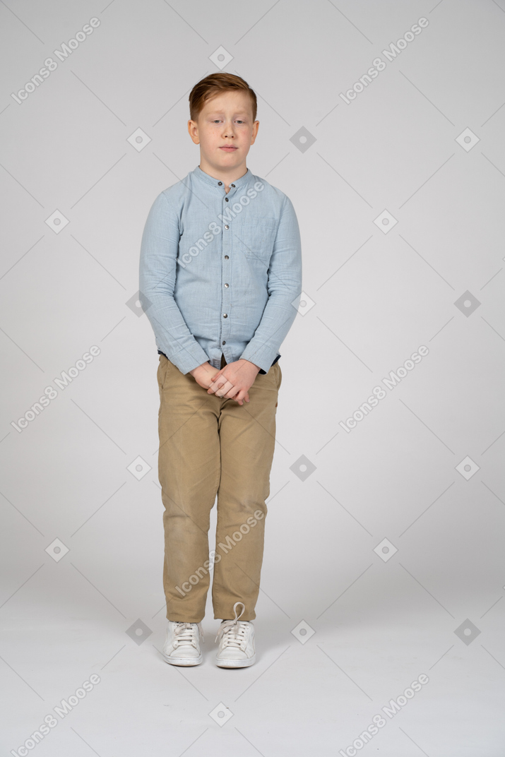 Vista frontal de un niño tímido mirando hacia abajo