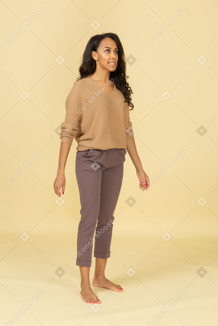 Three-quarter view of a young female in casual clothes clenching teeth