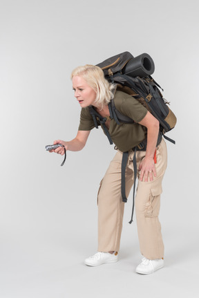 Carrying backpack mature female tourist using dictaphone