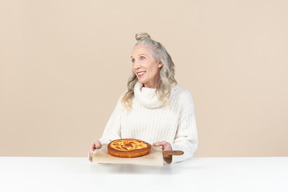 Elegant old woman pleased with a freshly baked pie