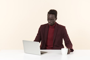 Elegante hombre negro sentado a la mesa en la oficina