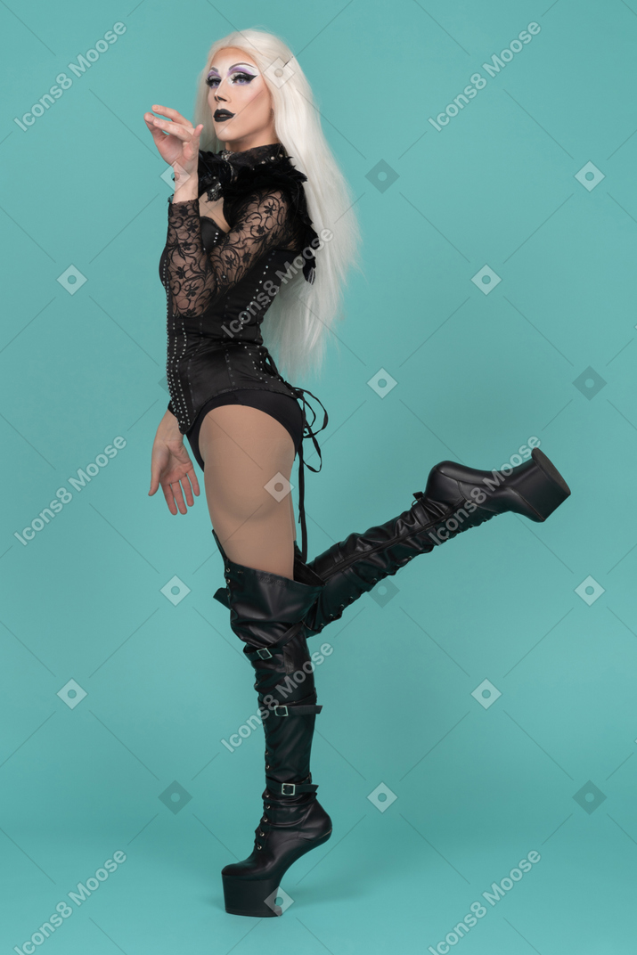 Side view of transvestite standing on one leg with pinch gesture