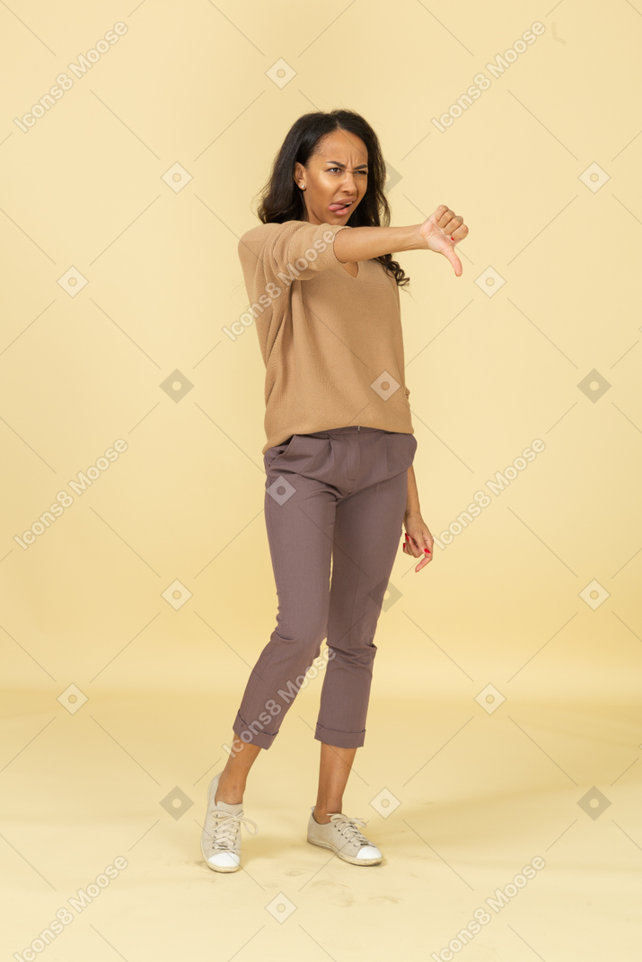 Вид в три четверти темнокожей молодой женщины, показывающий большой палец вниз