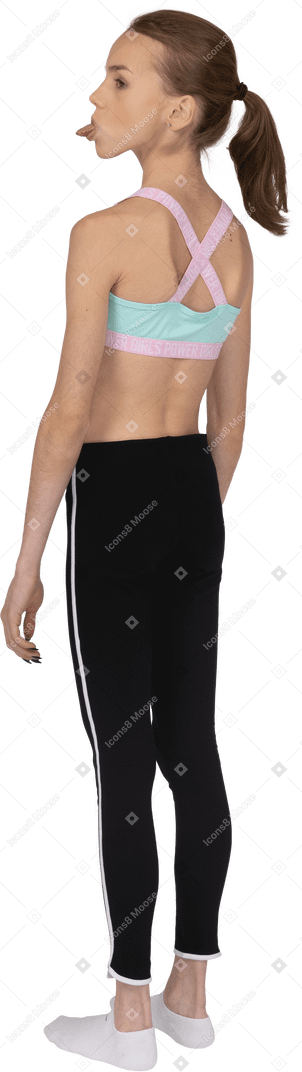 Dreiviertel-rückansicht eines jugendlichen mädchens in sportbekleidung, das eine zunge herausstreckt und beiseite schaut