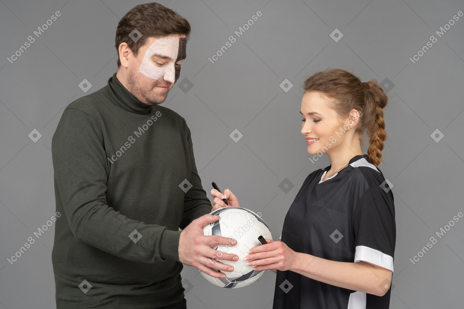 Female football player signing a ball for the fan