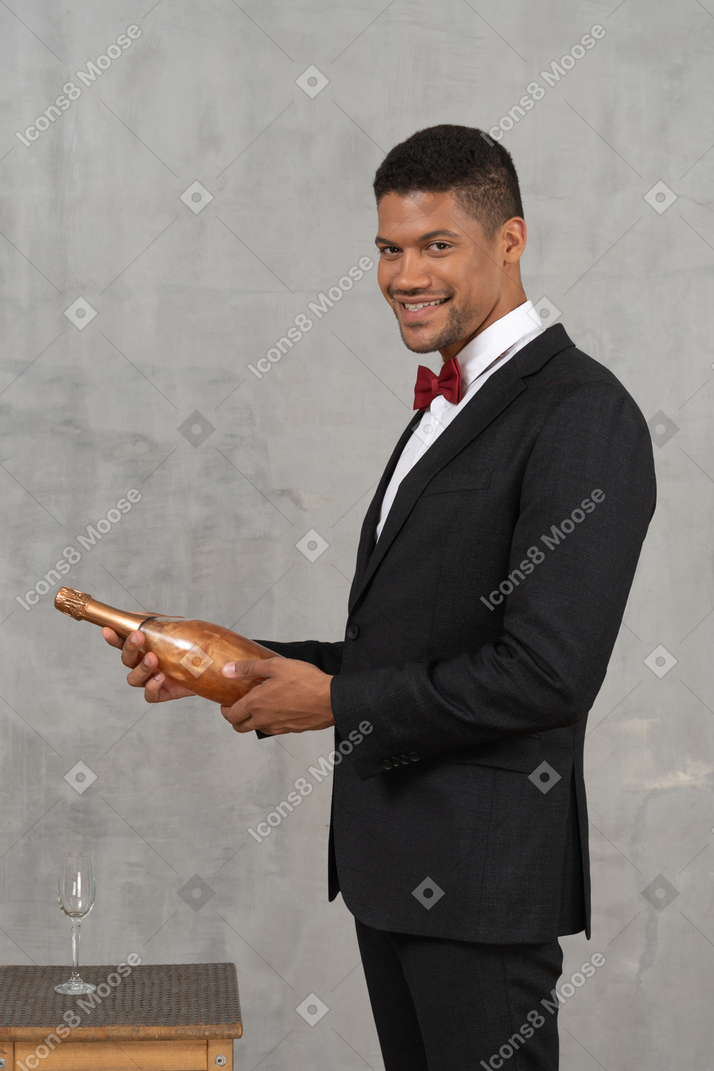 Smiling man holding a champagne bottle and looking at camera