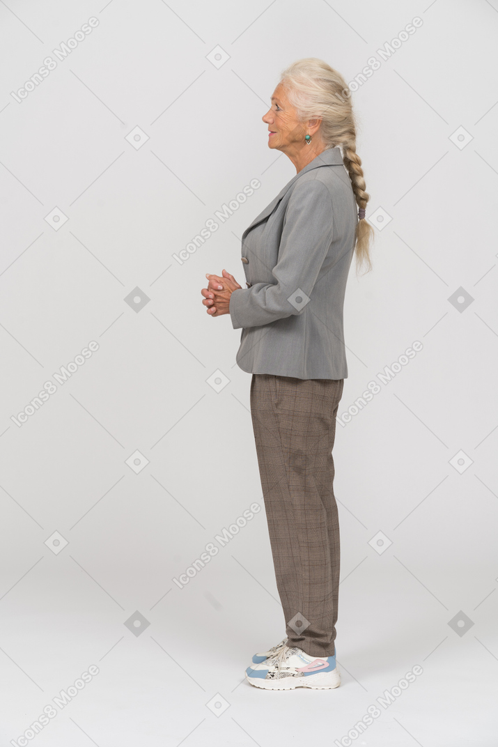 Vecchia donna in abito in piedi di profilo