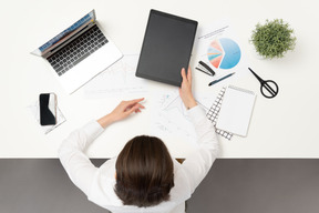 A female office worker at the table holding ipad