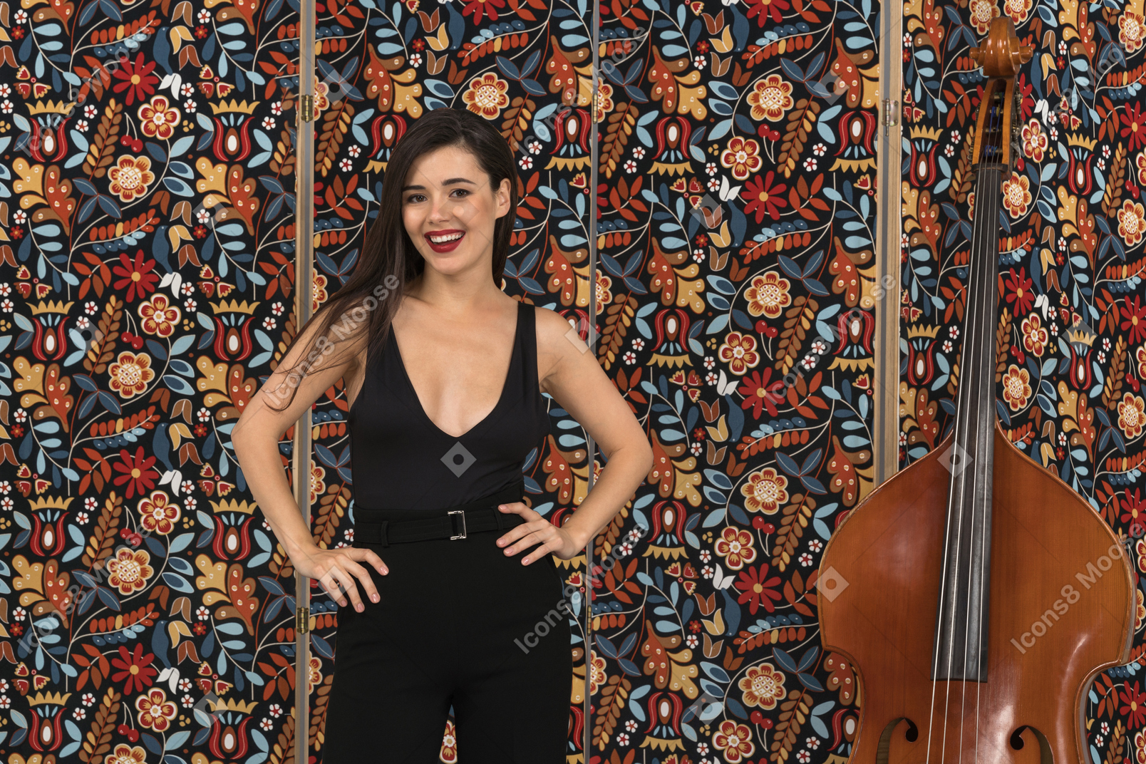 Smiling young woman standing with her arms akimbo next to a double-bass