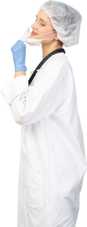 Vista lateral de uma jovem médica tentando tirar a máscara
