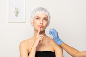 Surgeon holding scalpel near female patient's face