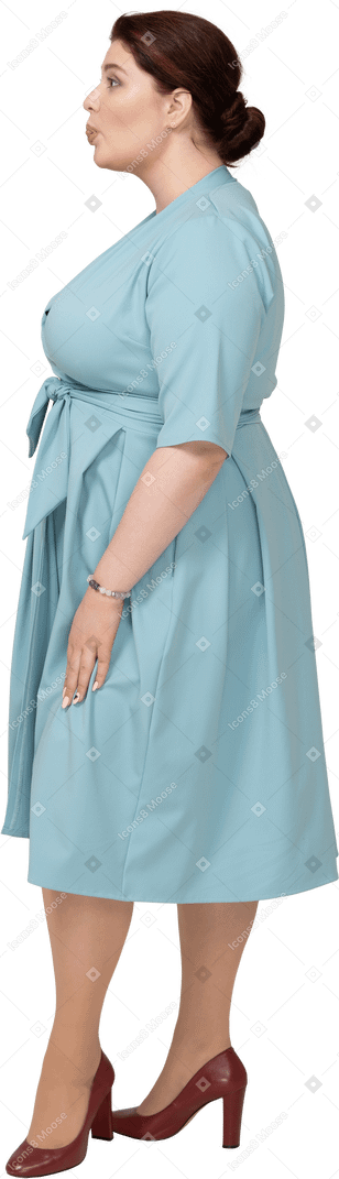 Женщина в синем платье корчит рожи, вид сбоку