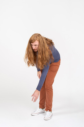 Front view of a young man in casual clothes bending down