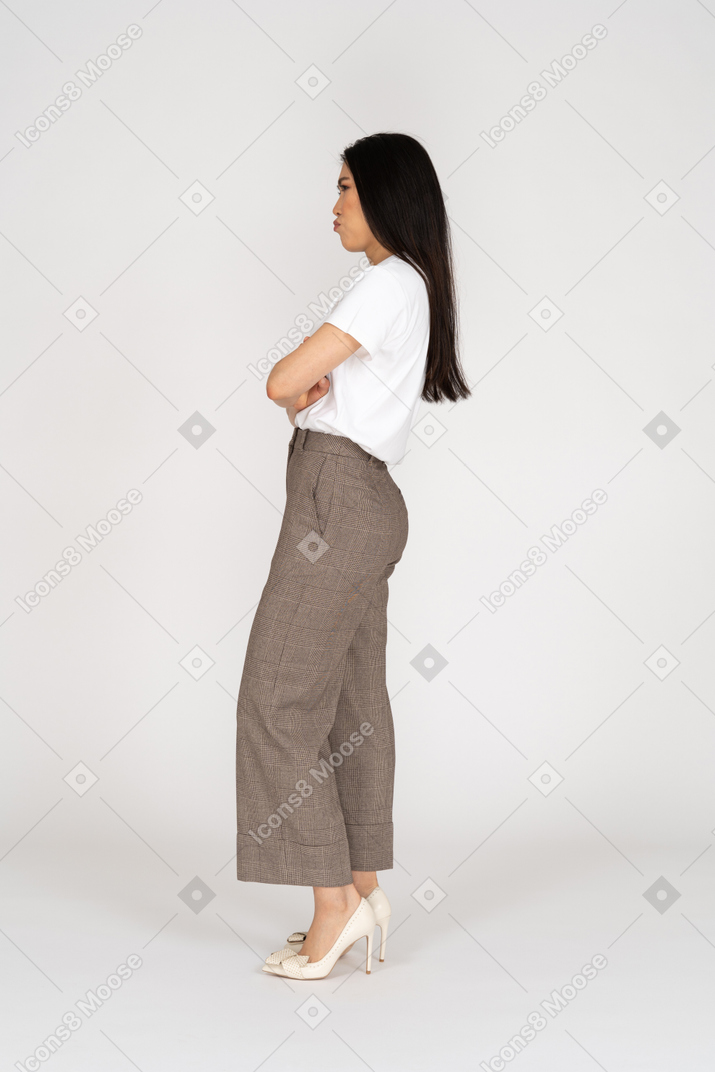 Side view of a pouting young lady in breeches and t-shirt crossing hands