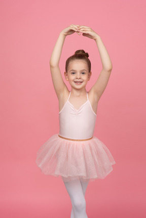 Little girl wearing a tutu and standing in ballet position