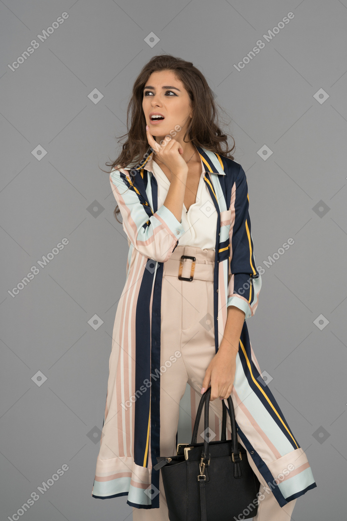 Beautiful young woman thinking about a better plan and holding black handbag