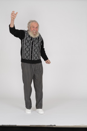 Front view of cheerful old man standing and raising his arm