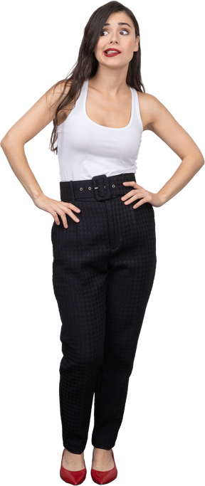 Front view of a perplexed young female in office clothing putting hands on hips