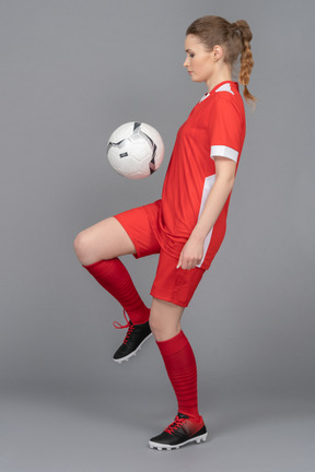 A serious female player kicking a ball