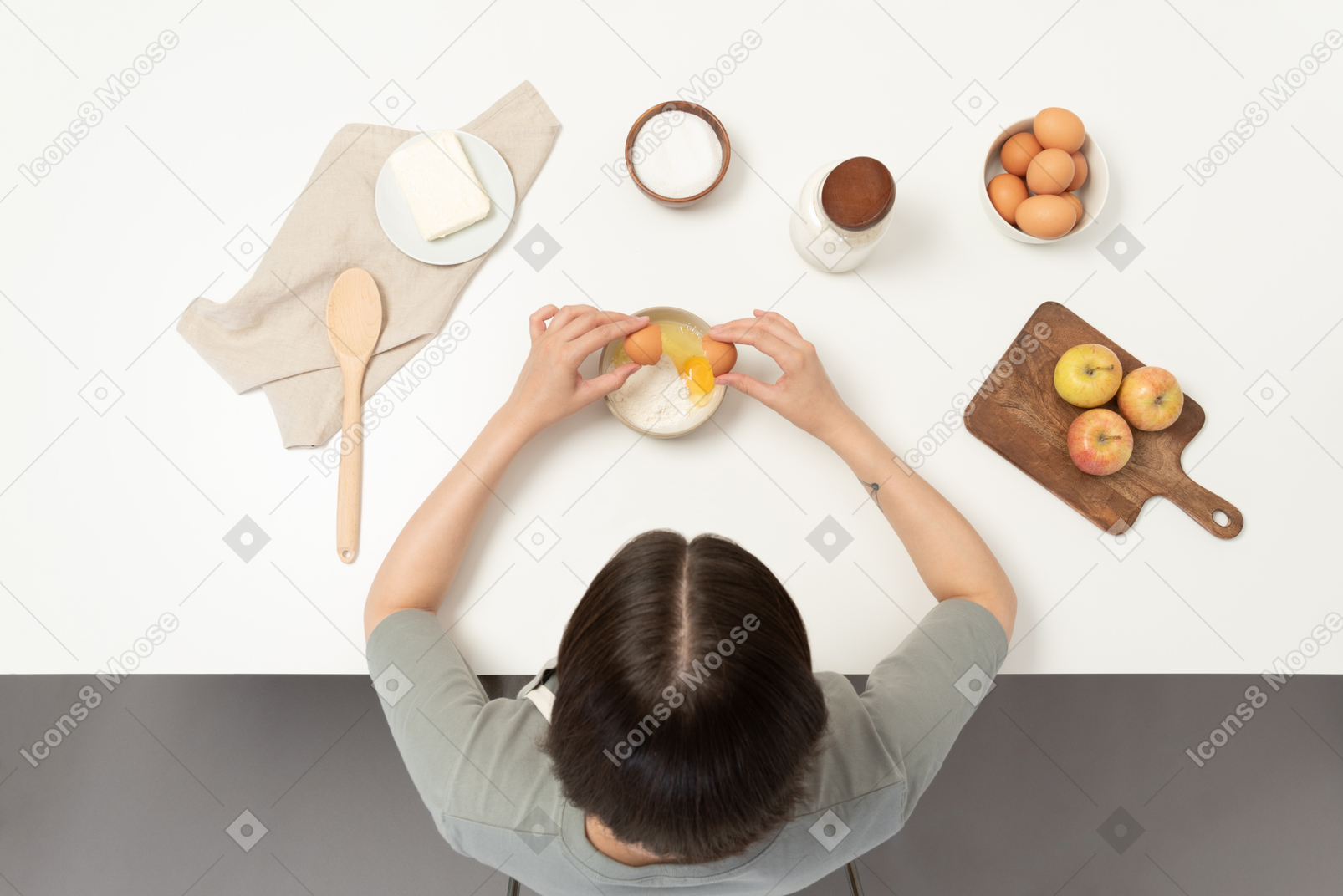 A female baker adding eggs to the flour