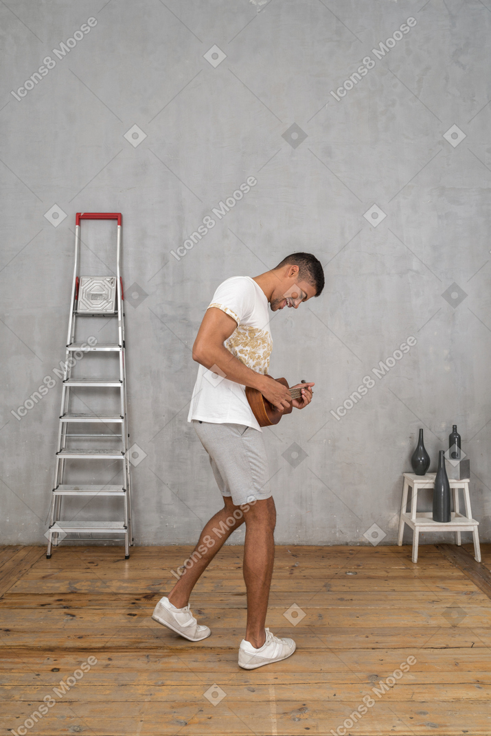 Vue latérale d'un homme se balançant sur un ukulélé