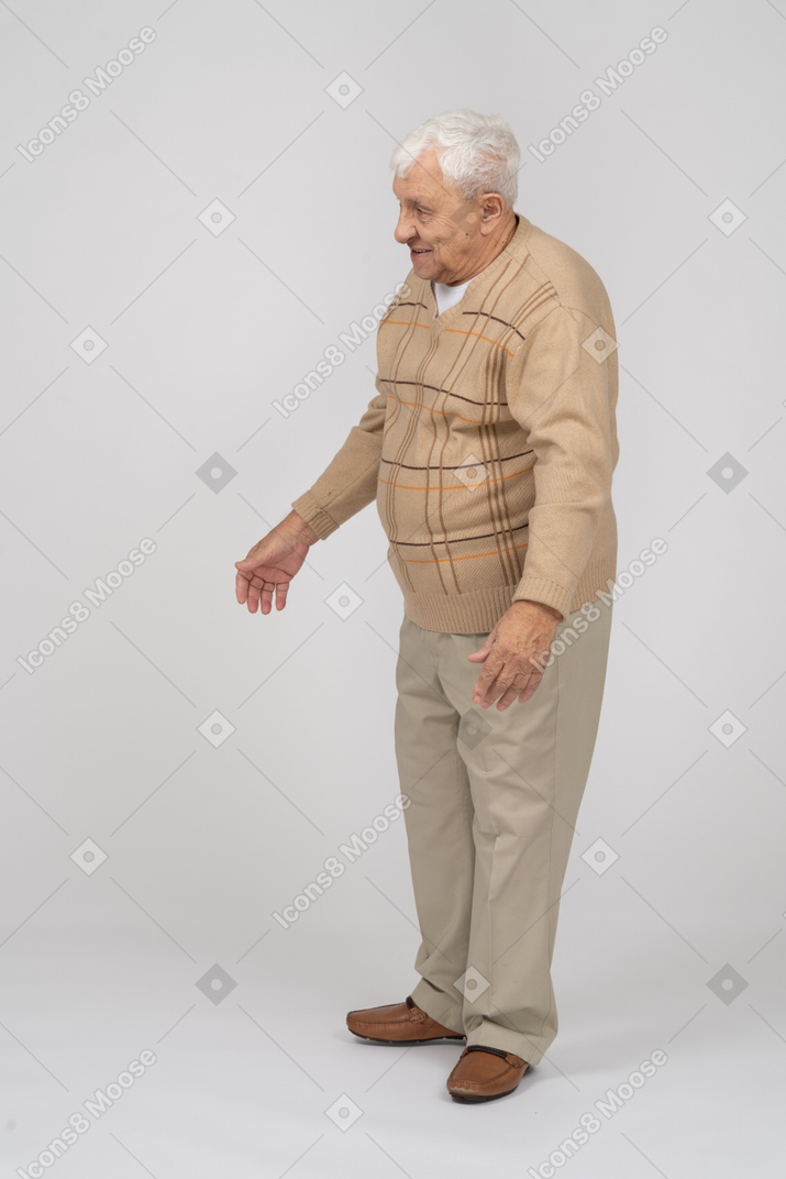 Side view of an old man in casual clothes standing with outstretched arms