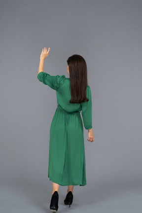 Back view of a greeting young lady in green dress