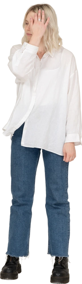 Front view of a blonde female  raising hand and hiding face