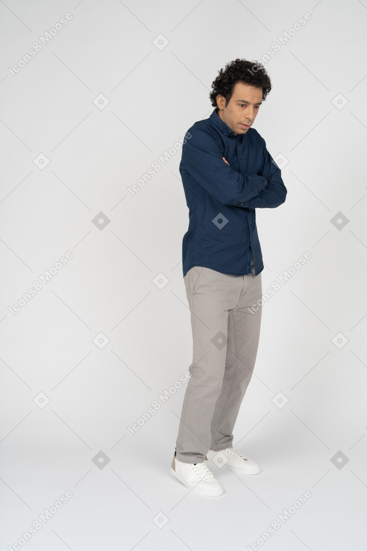 Vista frontal de um homem chateado em roupas casuais, posando com os braços cruzados