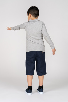 Rear view of a boy stretching hand