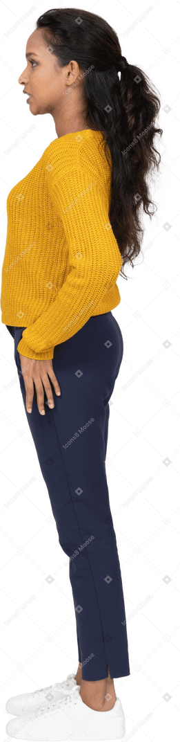 Vue latérale d'une fille en vêtements décontractés debout avec la main sur la hanche et faisant des grimaces