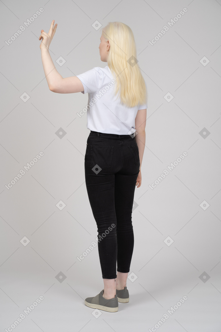 Vista traseira de uma jovem mostrando sinal de mão v