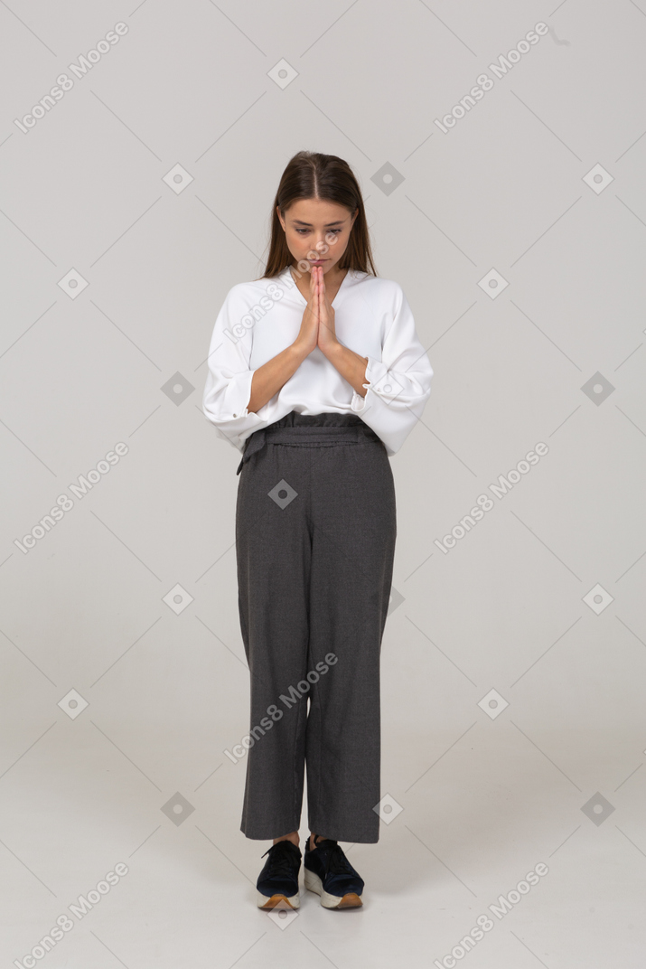 Vista frontale di una giovane donna in preghiera in abiti da ufficio che si tiene per mano insieme