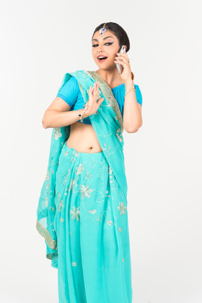 Young indian dancer in blue sari talking on the phone