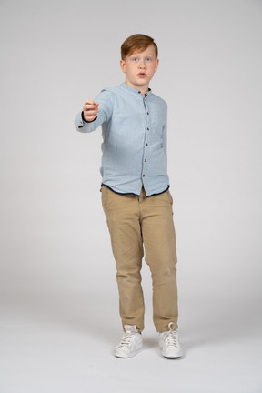 Front view of a boy standing with extended arm and looking at camera