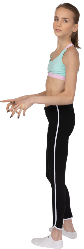 Vista lateral de una jovencita en ropa deportiva extendiendo los dedos y mirando a la cámara