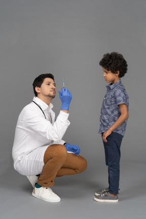 Médico mostrando seringa para um menino