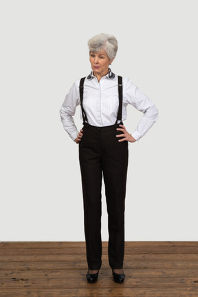 Full-length of an old female in suspenders putting hands on hips winking